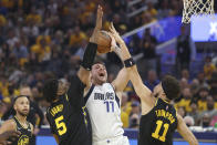 Dallas Mavericks guard Luka Doncic (77) shoots between Golden State Warriors center Kevon Looney (5) and guard Klay Thompson (11) during the first half of Game 1 of the NBA basketball playoffs Western Conference finals in San Francisco, Wednesday, May 18, 2022. (AP Photo/Jed Jacobsohn)