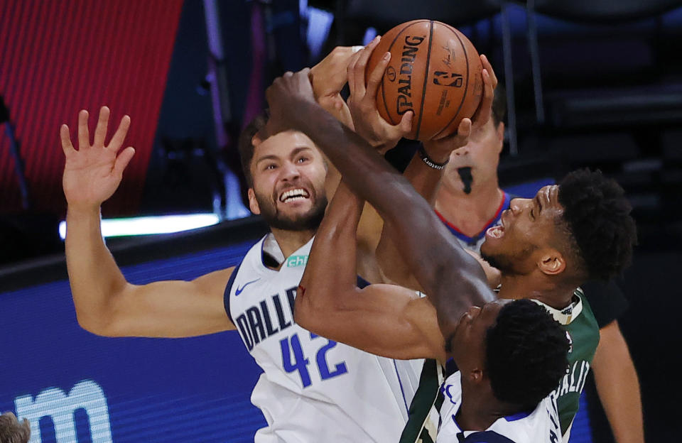 Milwaukee Bucks' Giannis Antetokounmpo draws a foul from Dallas Mavericks' Maxi Kleber (42) as Dorian Finney-Smith defends during an NBA basketball game Saturday, Aug. 8, 2020, in Lake Buena Vista, Fla. (Kevin C. Cox/Pool Photo via AP)