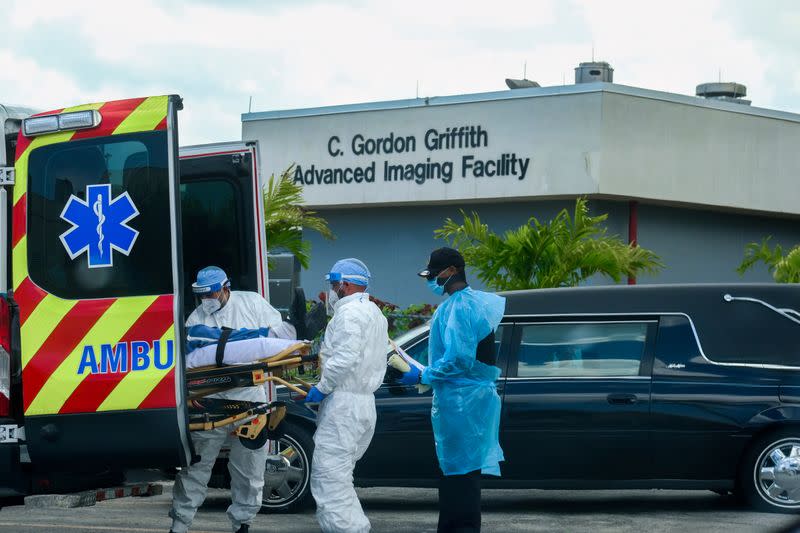 Emergency Medical Technicians (EMT) arrive with a patient while a funeral car begins to depart at North Shore Medical Center where the coronavirus disease (COVID-19) patients are treated, in Miami