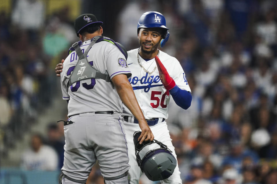Los Angeles Dodgers' Mookie Betts (50) hugs Colorado Rockies catcher Elias Diaz after getting caught stealing home during the sixth inning of a baseball game Friday, Aug. 11, 2023, in Los Angeles. (AP Photo/Ryan Sun)