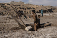 Ajab Gul's young sons dig sand from the riverbed in Kamar Kalagh village near Herat, Afghanistan, Friday, Nov. 26, 2021. A full day’s work will earn them the equivalent of about $2. (AP Photo/Petros Giannakouris)