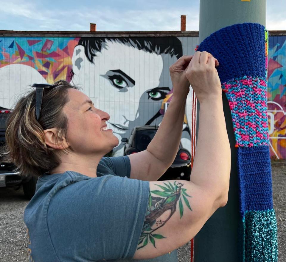 Volunteer Carla Giacobone works on yarn art on Sixth Street NW in downtown Canton. Yarn art will decorate poles and buildings, including in the Court Avenue NW area. The installation is on display until September.