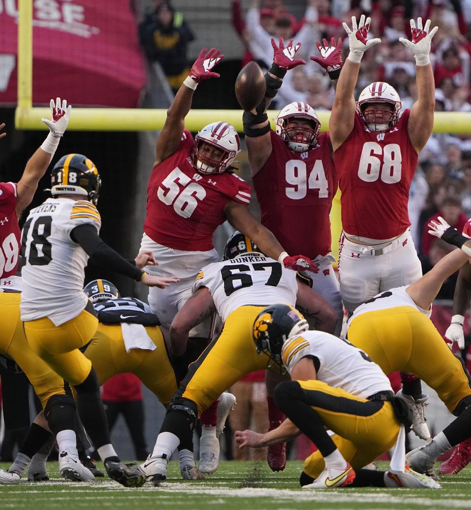 Iowa place kicker Drew Stevens (18) kicks field goal over Wisconsin defensive end Rodas Johnson (56), defensive end Gio Paez (94) and defensive end Ben Barten (68) during the fourth quarter of their game Saturday, October 14, 2023 at Camp Randall Stadium in Madison, Wisconsin. Iowa beat Wisconsin 15-6.