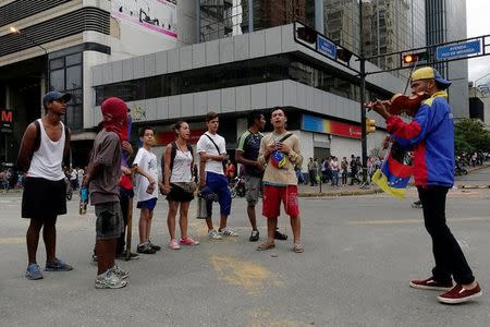 Manifestantes cantan el himno nacional de Venezuela cerca del violinista Wuilly Arteaga mientras bloquean una calle de Caracas durante una protesta contra el Gobierno del presidente Nicolás Maduro, Venezuela, 19 de julio de 2017. REUTERS/Carlos Garcia Rawlins