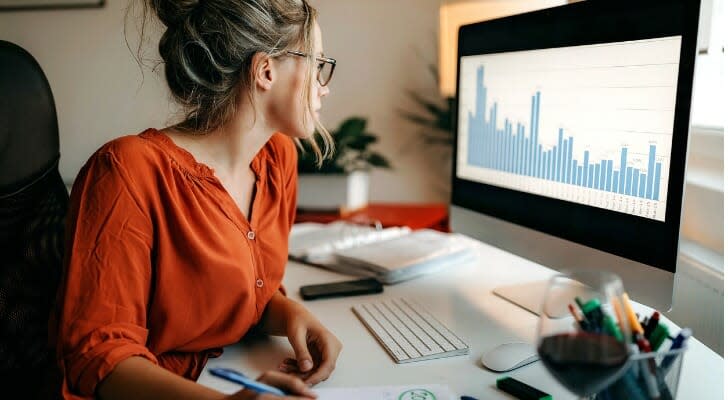 A woman looks over a graph on her computer. President Joe Biden wants to raise the long-term capital gains tax rate for the wealthiest Americans.