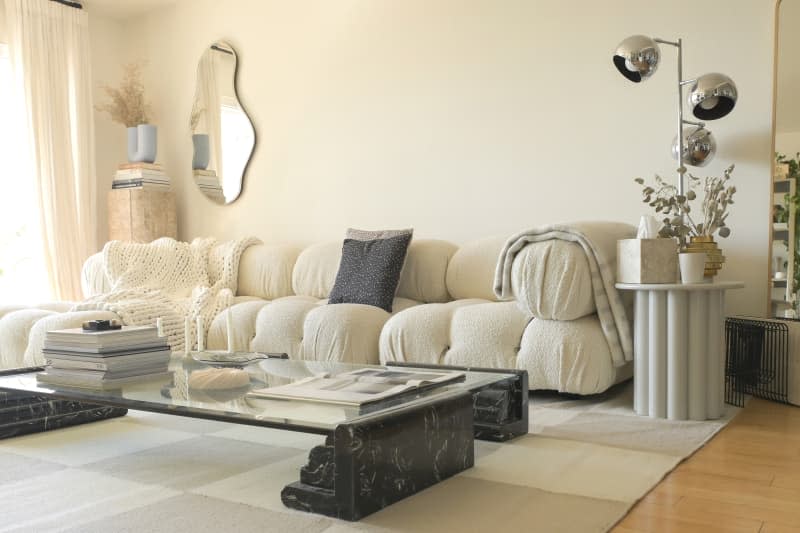 white living room with large white cozy sofa and large unique coffee table