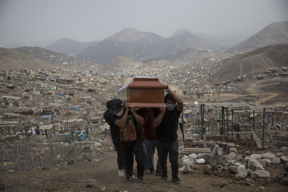 Relatives carry the coffin of a man who supposedly died of COVID-19 complications, at the Nueva Esperanza cemetery on the outskirts of Lima, Peru, Thursday, May 28, 2020. (AP Photo/Rodrigo Abd)