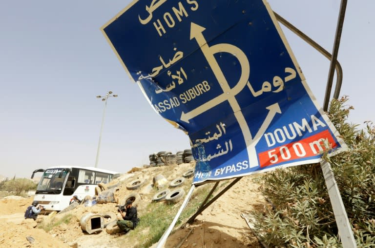 A smashed sign stands by a road at the entrance of Harasta in Eastern Ghouta near Damascus on March 22, 2018, as buses wait to evacuate rebels from the town following a deal brokered by Syrian regime ally Russia