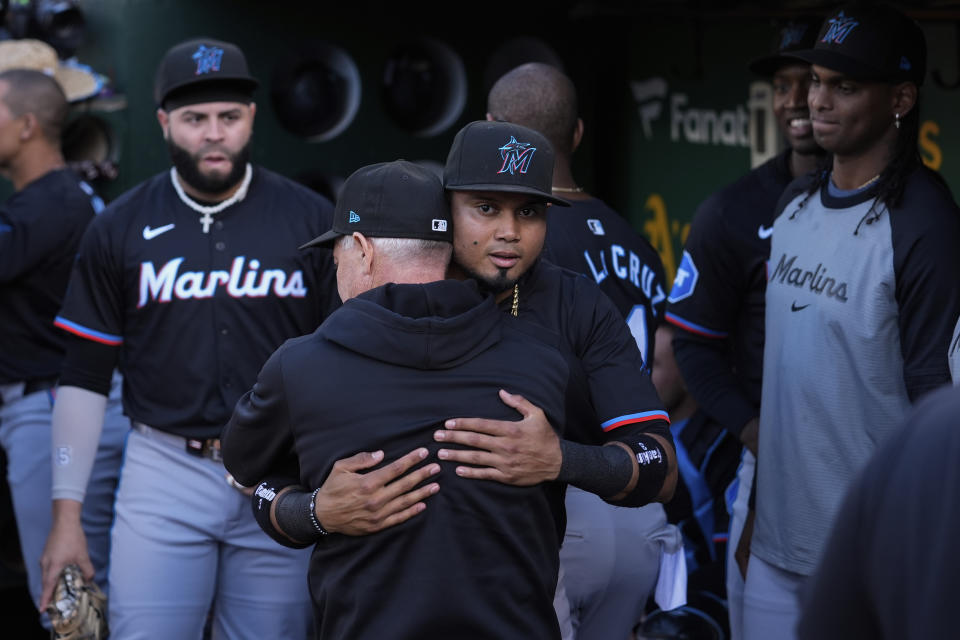 Miami Marlins' Luis Arraez, center, is hugged by a staff member in the dugout after being traded to the San Diego Padres before the team's baseball game against the Oakland Athletics, Friday, May 3, 2024, in Oakland, Calif. (AP Photo/Godofredo A. Vásquez)