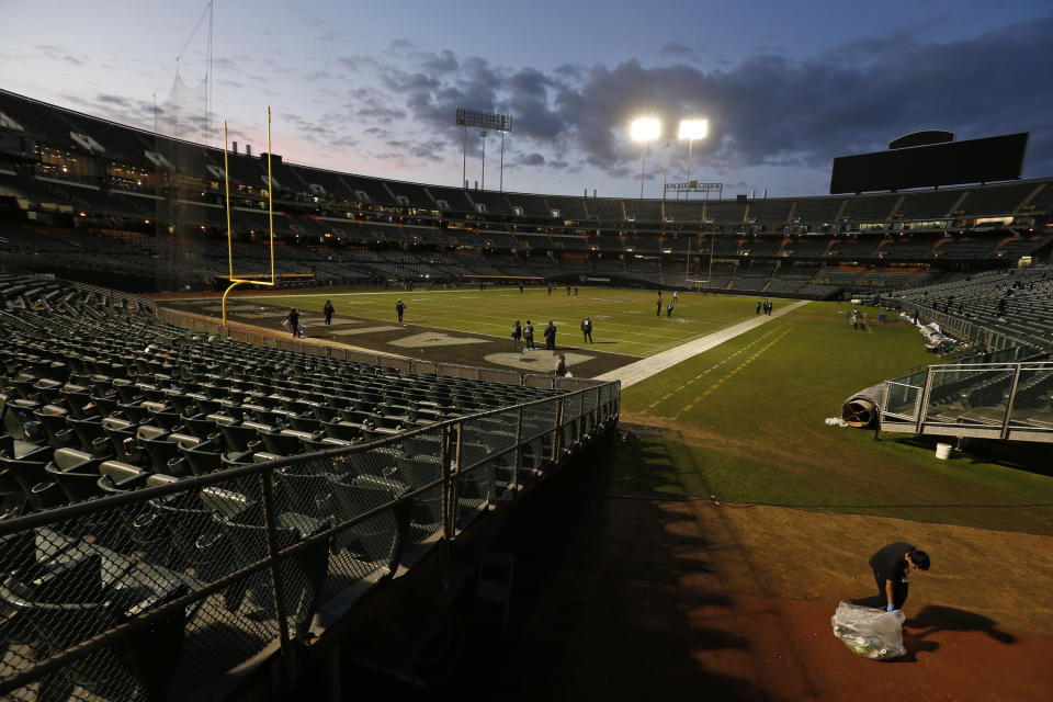 A stadium worker, right, picks up trash after an NFL football game between the Oakland Raiders and the Jacksonville Jaguars in Oakland, Calif., Sunday, Dec. 15, 2019. The game was the Raiders final scheduled game in Oakland. (AP Photo/D. Ross Cameron)