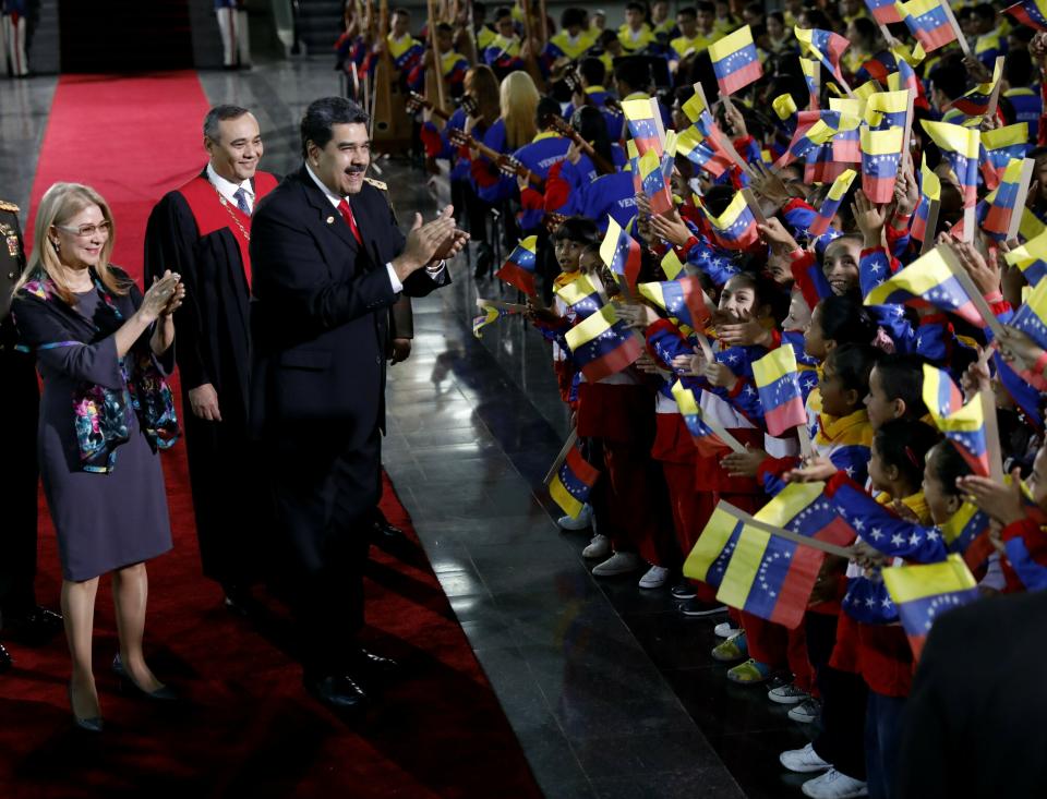 Venezuela's President Nicolas Maduro and first lady Cilia Flores stop to greet flag-waving children upon arrival to the Supreme Court for Maduro's inauguration ceremony in Caracas, Venezuela, Thursday, Jan. 10, 2019. Maduro was sworn in to a second term amid international calls for him to step down and a devastating economic crisis. Behind is Supreme Court President Maikel Moreno. (AP Photo/Ariana Cubillos)