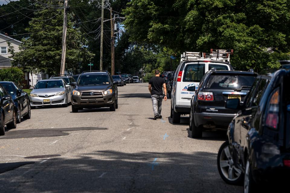 Aug 18, 2023; Clifton, New Jersey, USA; A man walks by parked cars on Pershing Road. Mandatory Credit: Anne-Marie Caruso-The Bergen Record