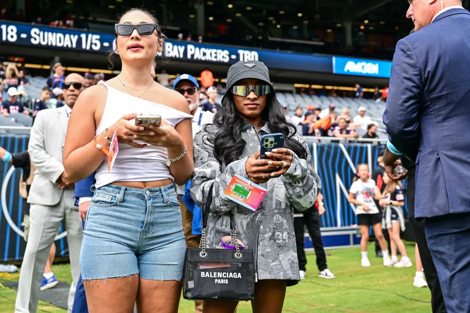 U.S. gymnast Simone Biles, right, stands on the sideline before the game between the Chicago Bears and the Cincinnati Bengals at Soldier Field.