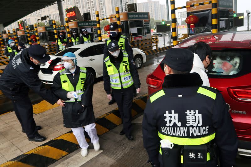 FILE PHOTO: Police officers wearing masks check the boot of a car for smuggled wild animals following the outbreak of a new coronavirus, at an expressway toll station on the eve of the Chinese Lunar New Year celebrations, in Xianning