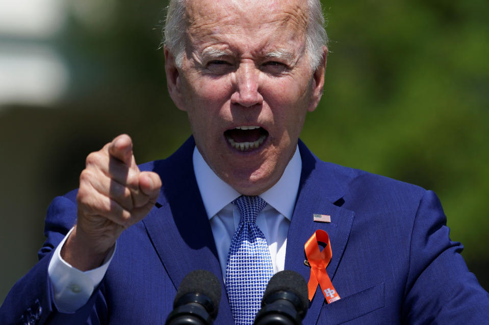 President Biden points toward the crowd as he stands at a microphone.