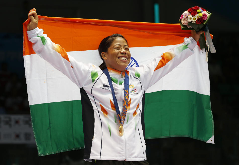 FILE - In this Wednesday, Oct. 1, 2014, file photo, India's M.C. Mary Kom holds the Indian national flag and celebrates her gold medal in the women's flyweight (48-51kg) final boxing match at the 17th Asian Games in Incheon, South Korea. Kom, whose inspirational life story spawned films and books, qualified for a third Olympics. (AP Photo/Kin Cheung, File)