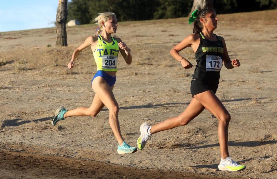 Roosevelt High senior Alyana Chávez (3rd, 19:34.33) leads Taft Union senior Maya Katz in the Division IV race at the CIF Central Section cross country championships at Woodward Park on Nov. 16, 2023.