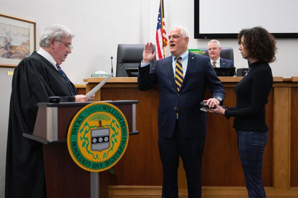 Bucks County President Judge Wallace Bateman issues the oath of office to newly re-elected District Attorney Matt Weintraub as his wife, Kathleen, hold the Bible.  New Bucks County Judge Stephen Corr watches the ceremony Monday at the county administration building in Doylestown.