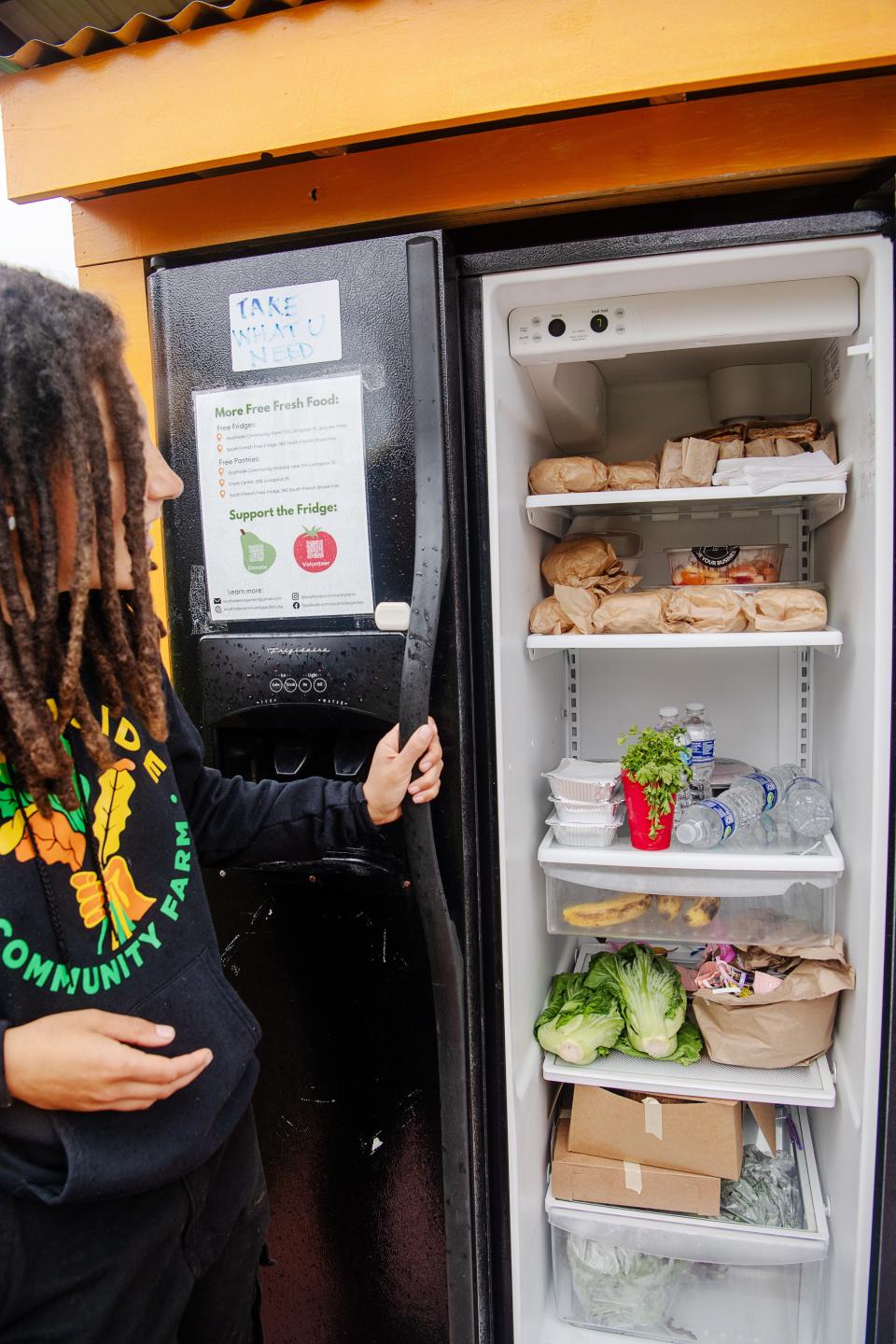 Southside Community Farm manager Chloe Moore opens a refrigerator of free food at the farm on Livingston Street in Asheville, April 11, 2024.
