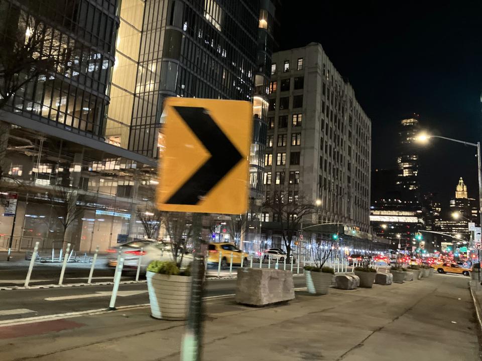 <p>A sample photo from the iPhone SE (2022), showing a road sign in front of some buildings at night.</p>
