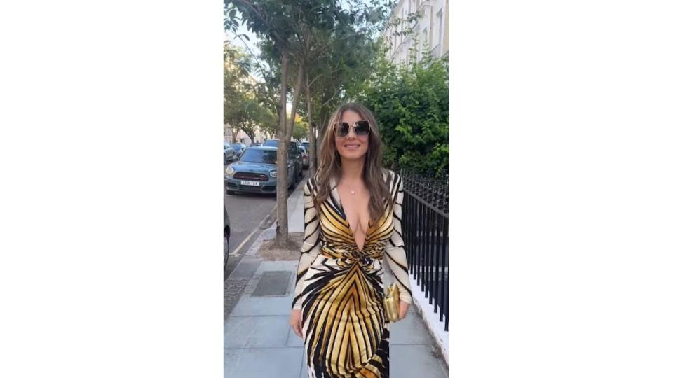 Elizabeth Hurley walking down a street in an animal-print dress