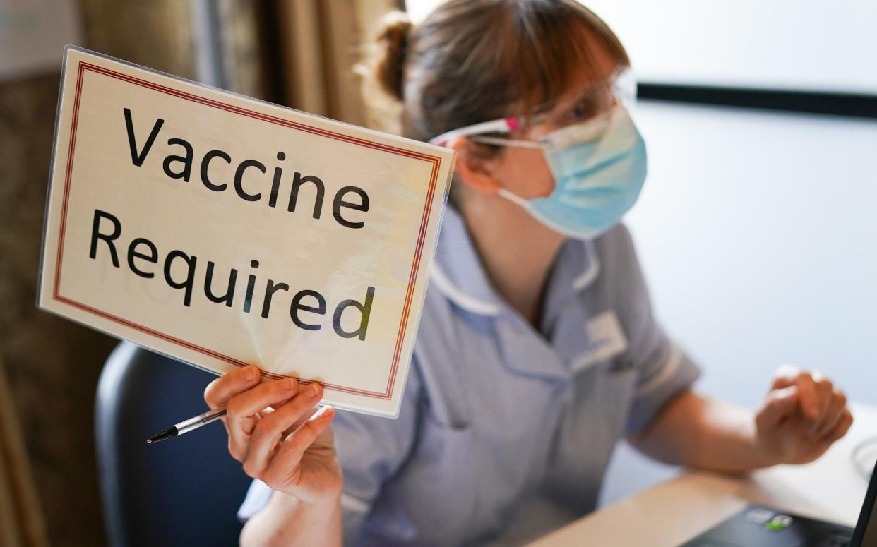 A member of the medical staff holds a sign indicating she has briefed a patient and is ready for a vaccine to be administered - Ian Forsyth /Getty Images Europe 