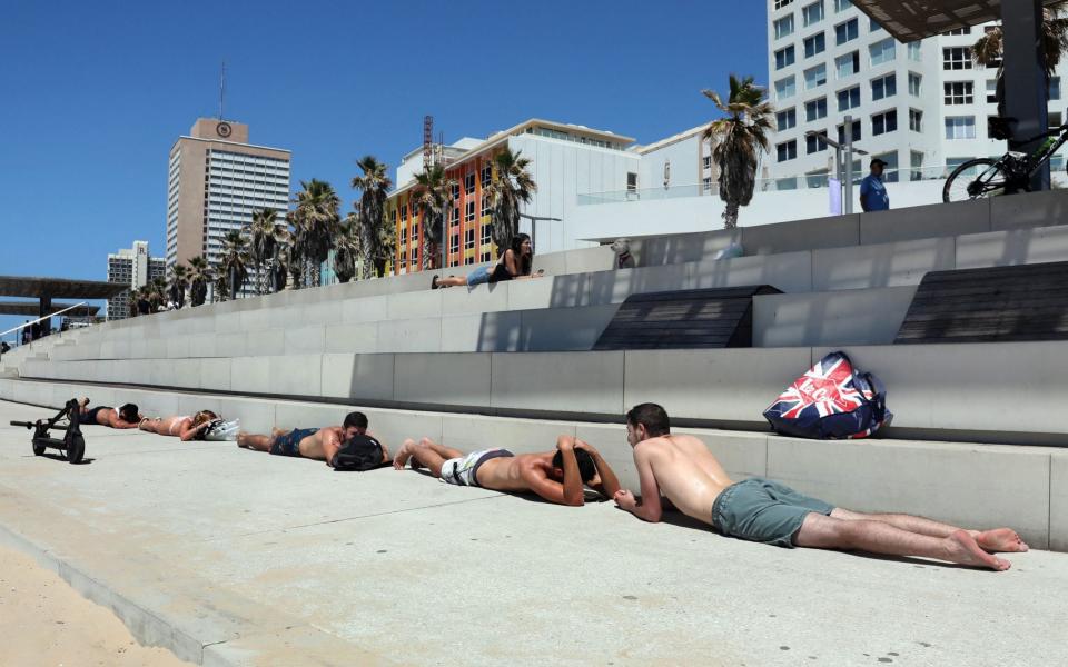 Israeli beachgoers take cover in the central city of Tel Aviv - AFP