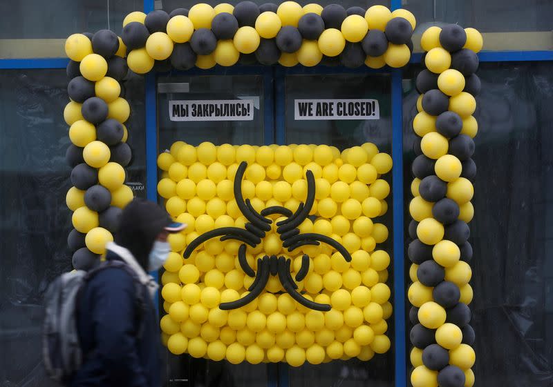 FILE PHOTO: A pedestrian wearing a protective mask walks past a warning sign outside a closed cafe in Moscow