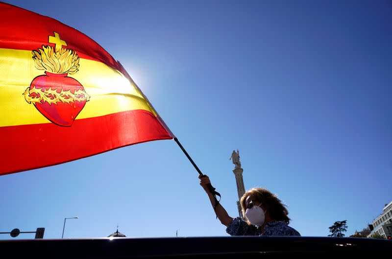 A woman waves a flag as she takes part in a protest against the state of emergency organized by the far-right party Vox on Spain's national day amid the outbreak of the coronavirus disease (COVID-19) in Madrid