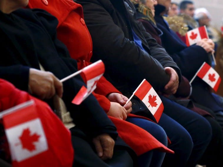 Syrian refugees hold Canadian flags as they take part in a welcome service at the St. Mary Armenian Apostolic Church at the Armenian Community Centre of Toronto in Toronto, December 11, 2015. REUTERS/Mark Blinch