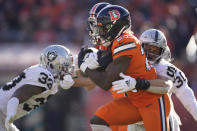 Denver Broncos running back Melvin Gordon III, middle, runs against Las Vegas Raiders linebacker Luke Masterson during the first half of an NFL football game in Denver, Sunday, Nov. 20, 2022. (AP Photo/David Zalubowski)