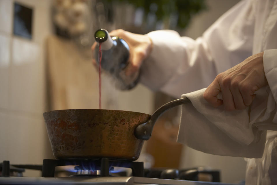 A chef pouring wine into a pot