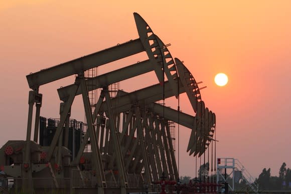 A group of oil pumps with the sun setting.