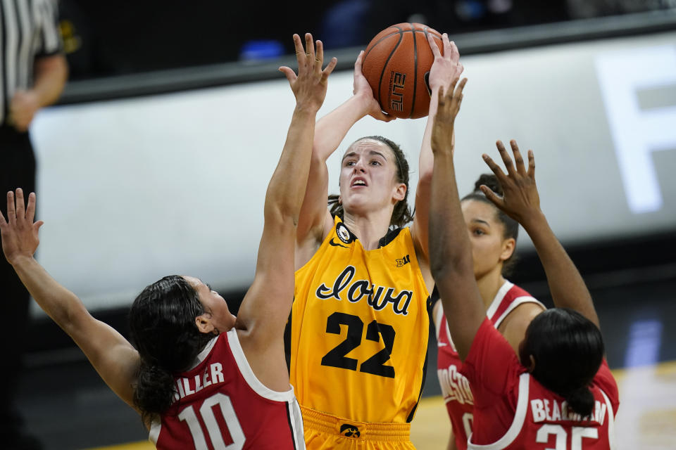 Iowa guard Caitlin Clark (22) drives to the basket between Ohio State guard Braxtin Miller (10) and forward Tanaya Beacham, right, during the first half of an NCAA college basketball game, Wednesday, Jan. 13, 2021, in Iowa City, Iowa. (AP Photo/Charlie Neibergall)