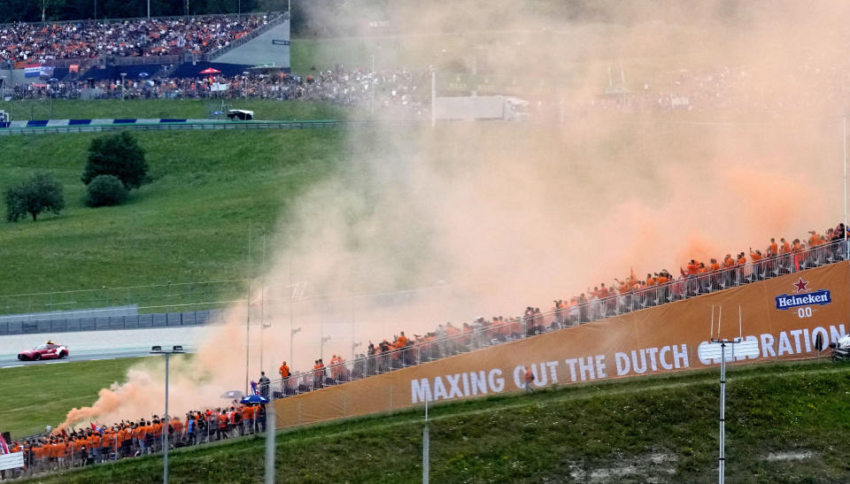Fans set off orange smoke flares as they arrive to cheer on Red Bull driver Max Verstappen of the Netherlands during the Austrian Formula One Grand Prix at the Red Bull Ring racetrack in Spielberg, Austria, Sunday, July 4, 2021. (AP Photo/Darko Bandic)