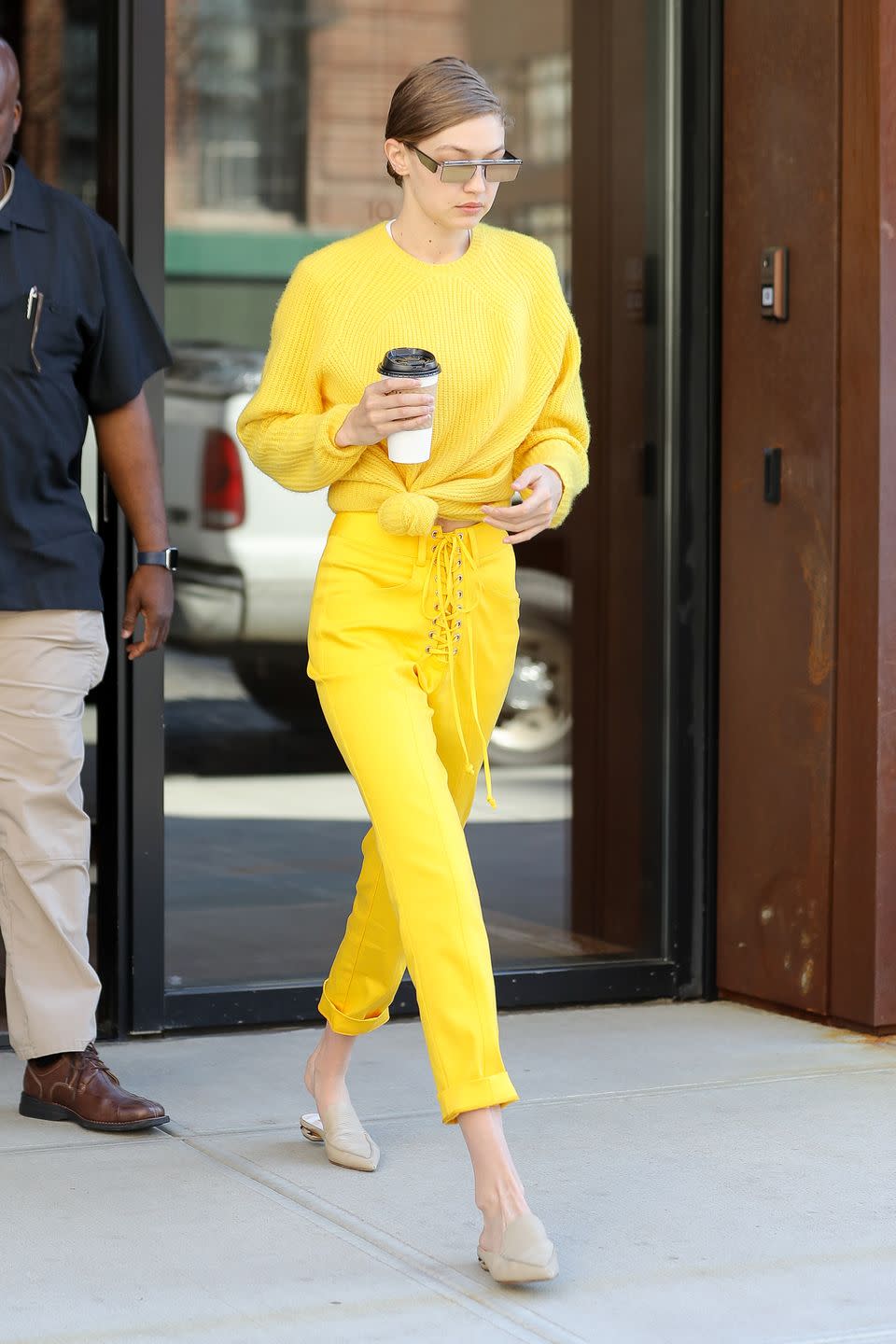 <p>In a bright yellow knotted pullover with matching lace-up pants and nude mules out in New York City. </p>