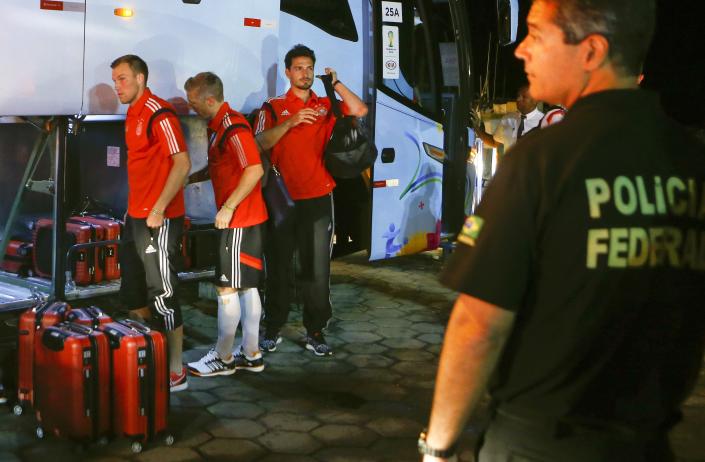A Brazilian federal policeman stands guard as Germany&#39;s national soccer team players (2nd R-L) Mats Hummels, Bastian Schweinsteiger and Kevin Grosskreutz leave a bus to take a ferry in the town of Santa Cruz Cabralia, north of Porto Seguro June 16, 2014. REUTERS/Arnd Wiegmann (BRAZIL - Tags: SPORT SOCCER WORLD CUP)