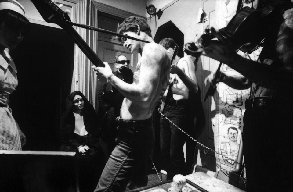 lou reed plays guitar standing in a crowded room with only pants on