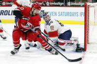 Carolina Hurricanes' Warren Foegele (13) tries to control the puck and shoot it at Florida Panthers' goaltender Chris Driedger (60) during the second period of an NHL hockey game in Raleigh, N.C., Sunday, March 7, 2021. (AP Photo/Karl B DeBlaker)