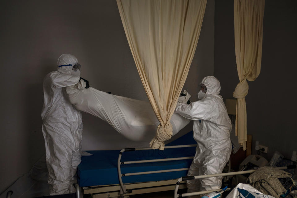Wearing protective suits to prevent infection, mortuary workers remove the body of an elderly person who died of COVID-19 from a nursing home in Barcelona, Spain, Friday, Nov. 13, 2020. Virus cases among the elderly are again on the rise across Europe, causing havoc and rising death tolls in nursing homes despite the lessons of a tragic spring. Authorities are in a race to save lives as they wait for crucial announcements on mass vaccinations. (AP Photo/Emilio Morenatti)