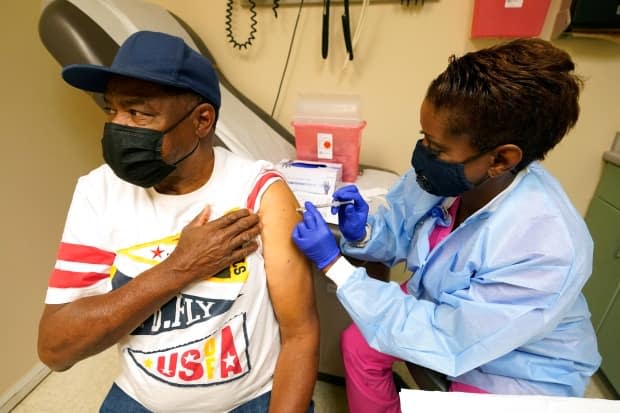 Wilbert Marshall, 71, looks away while receiving the COVID-19 vaccine from Melissa Banks, right, a nurse at the Aaron E. Henry Community Health Service Center in Clarksdale, Miss., April 7. Nearly half of American adults have received at least one dose of the COVID-19 vaccine, but there are some signs that rates are lower in Republican red states such as Mississippi than in Democrat-supporting blue states.