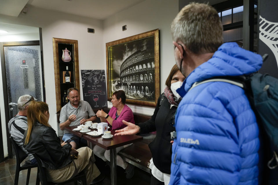 People gather at a bar in Rome, Sunday May 1, 2022. Face masks, for the first time since the start of the pandemic, are no longer required in supermarkets, bars, restaurants, shops and most workplaces throughout Italy, but remain mandatory on public transport, planes, trains and ships, theatres, cinemas, concert halls and for indoor sporting events. (AP Photo/Gregorio Borgia)