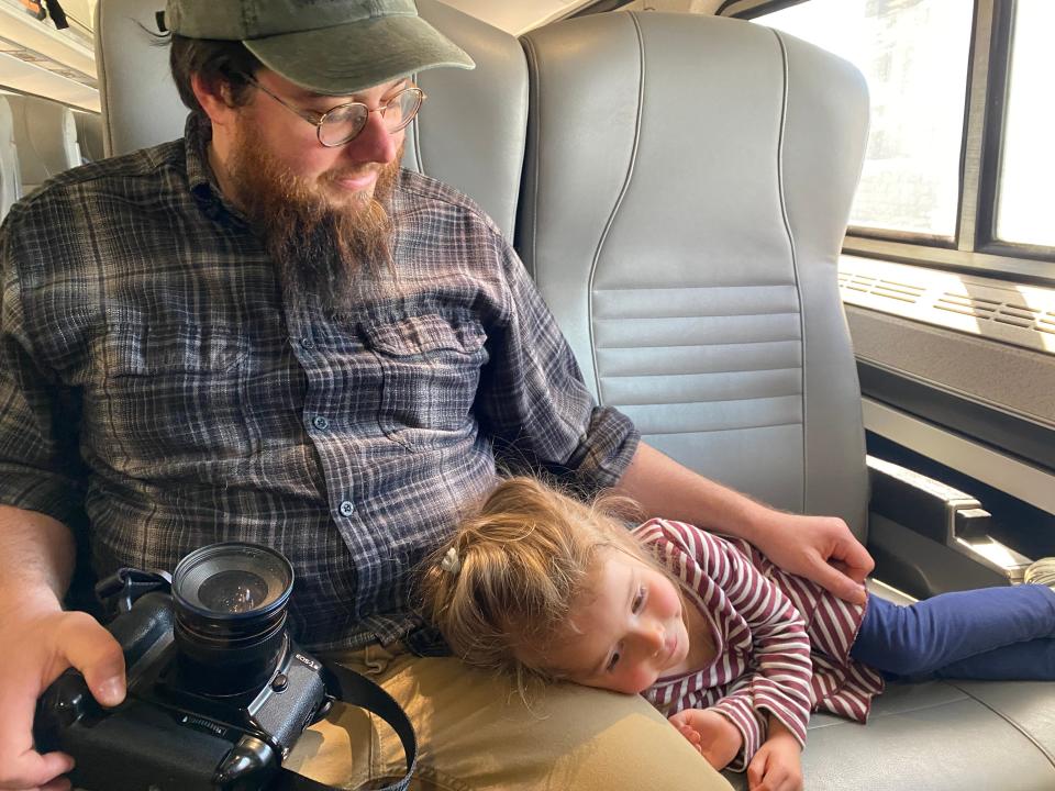 lauren's daughter resting on her dad's lap on an amtrak train