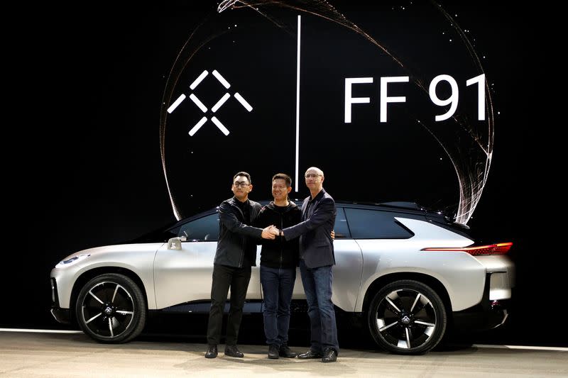 Richard Kim, YT Jia and Nick Sampson pose in front of a Faraday Future FF 91 electric car during an unveiling event at CES in Las Vegas