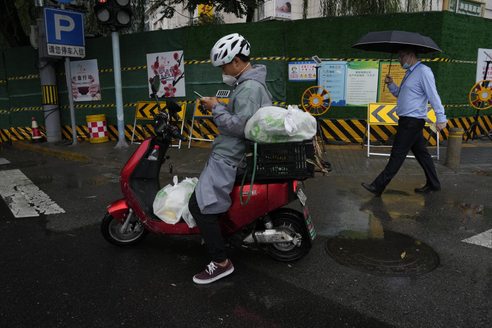 A delivery man checks his phone during a rainy day in Beijing, Thursday, Aug. 18, 2022. Some were killed with others missing after a flash flood in western China Thursday, as China faces both summer rains and severe heat and drought in different parts of the country. (AP Photo/Ng Han Guan)