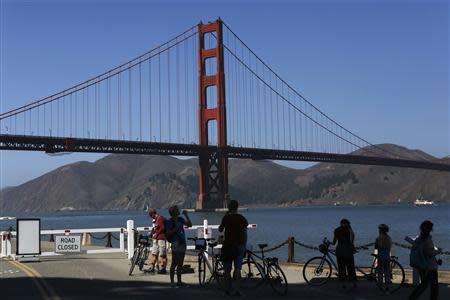 People stand near a closed road gate leading to Fort Point National Historic Site, which has been closed due to the federal government shutdown, in San Francisco, California October 2, 2013. REUTERS/Stephen Lam