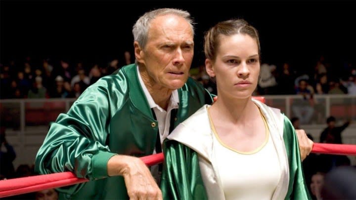 Clint Eastwood stands behind Hillary Swank in the boxing ring.