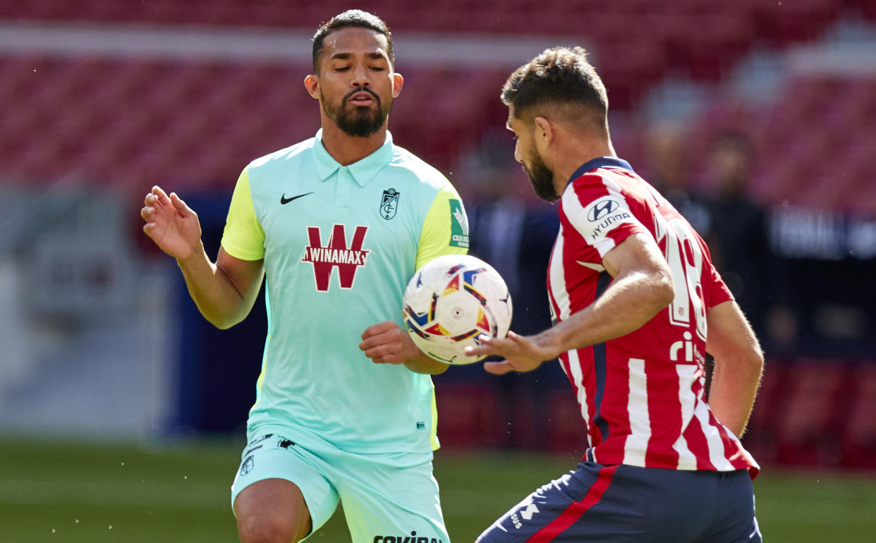 Jugadores del Granada y el Atlético de Madrid luchando por el balón.