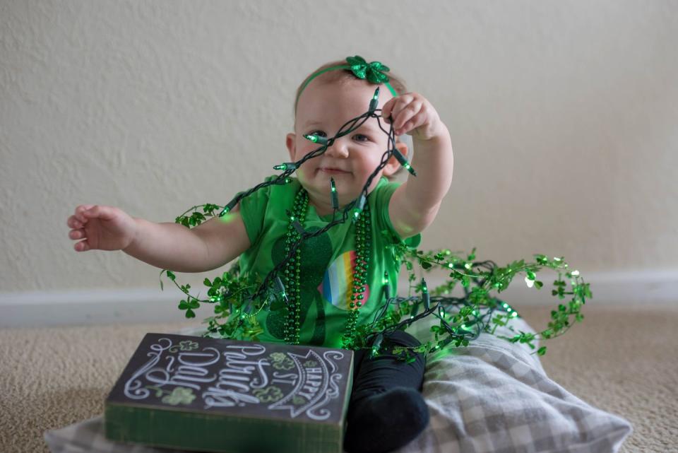 baby girl wearing green playing with st patricks' day decorations you might caption little miss shamrock on instagram