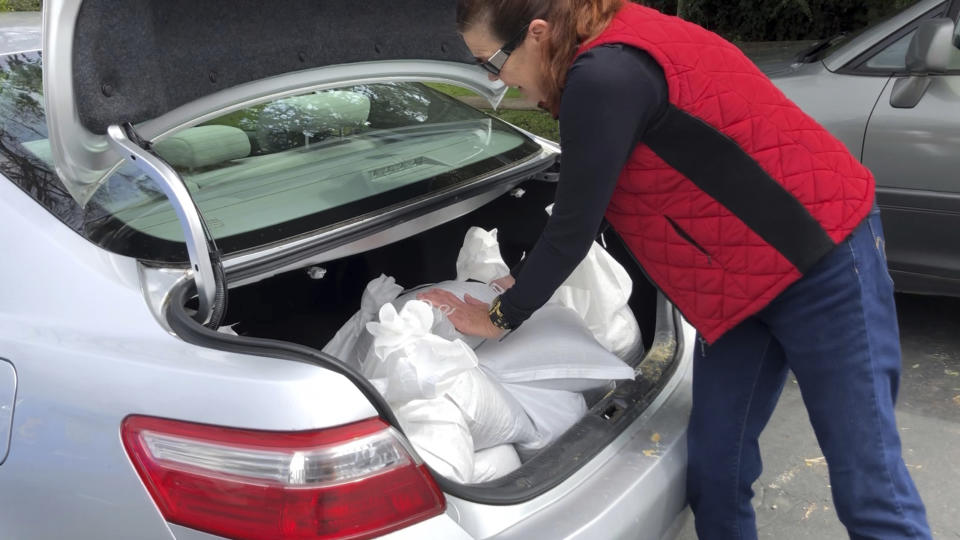 This photo provided by KEYT-TV shows people loading sandbags at a distribution center in Montecito, Calif., Tuesday, March 5, 2019. The Santa Barbara County Sheriff's Office on Tuesday ordered about 3,000 residents to evacuate ahead of a new storm expected to hit areas scarred by wildfires, including parts of Montecito hit by a disastrous debris flow just over a year ago. Residents of risk areas below the Thomas, Whittier and Sherpa fire burn scars were told to leave their homes by 4 p.m. (John Palminteri/KEYT-TV via AP)